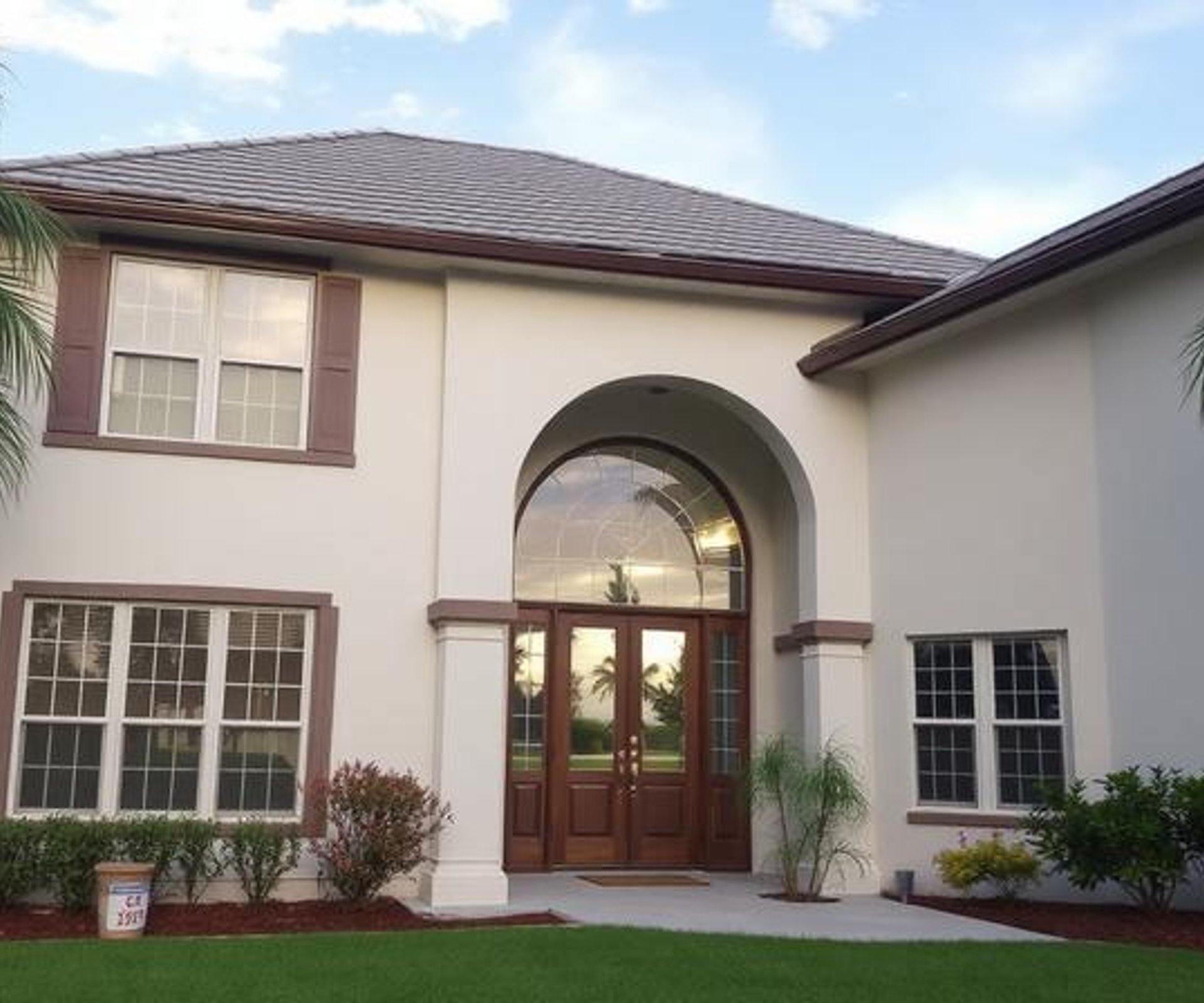 A large home surrounded by a spacious front yard, showcasing well-maintained grass and landscaping, painting company in Sarasota